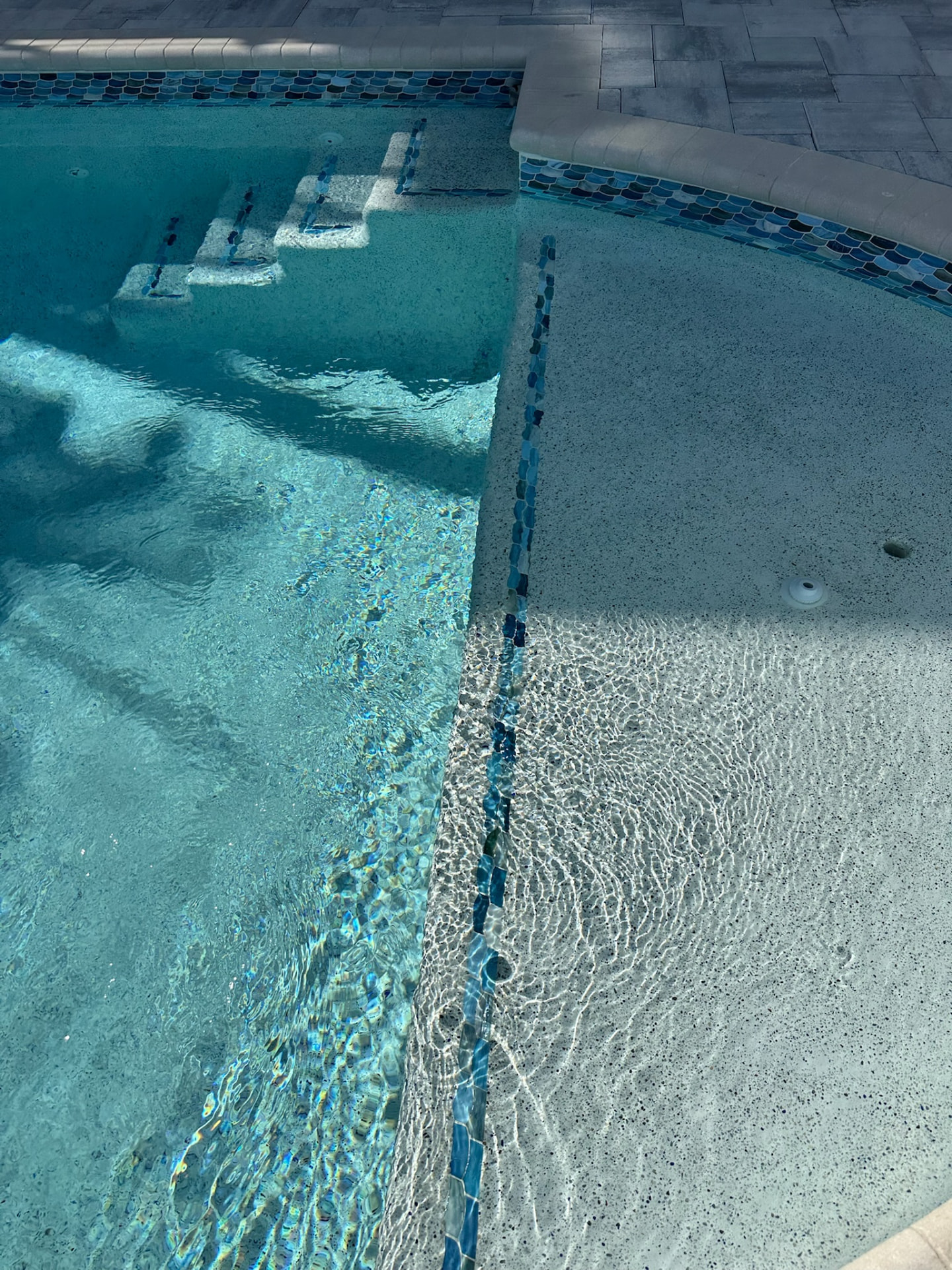 Close-up of glass mosaic waterline tile and sun shelf steps