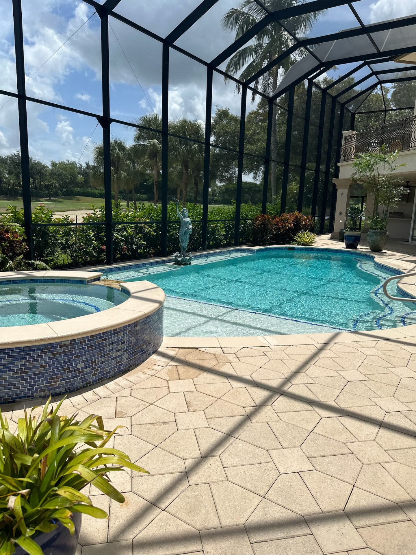 Screened pool enclosure with attached spa and golf course view