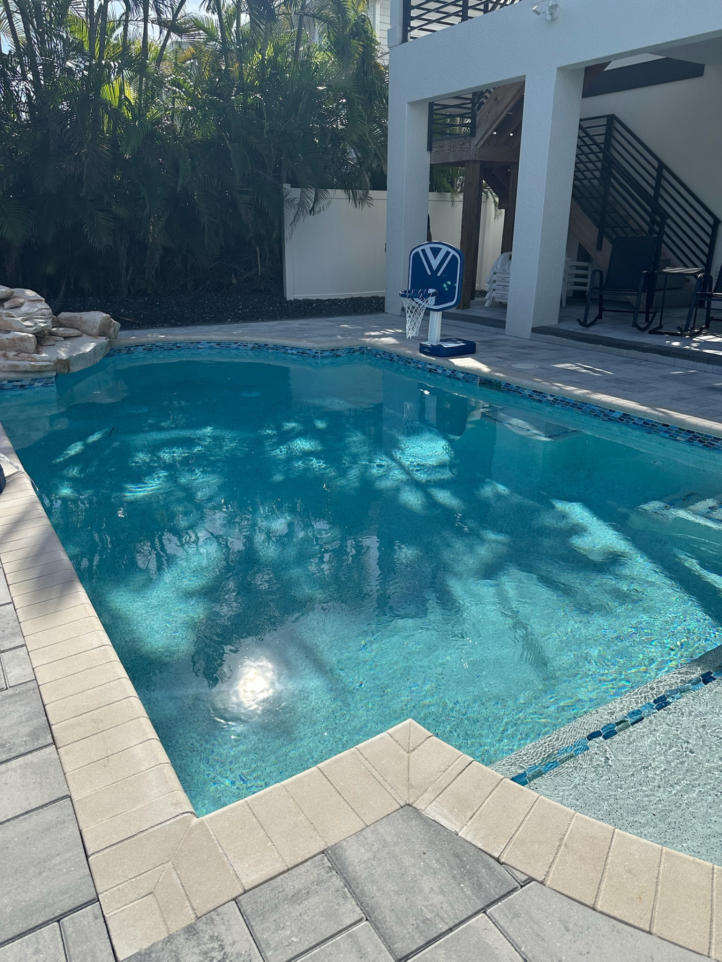 Renovated backyard pool with rock waterfall and poolside basketball hoop