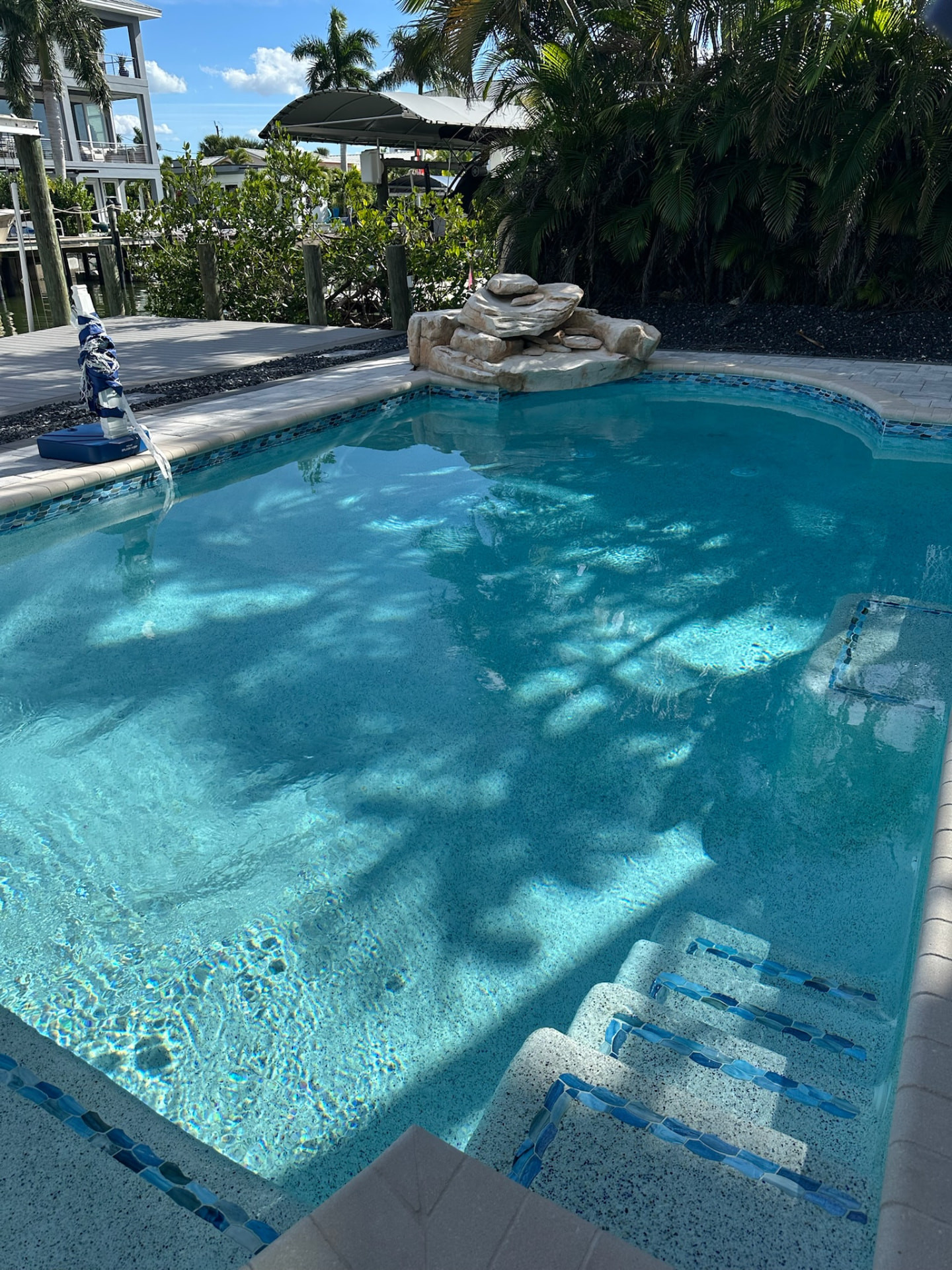 Canal-front pool with stacked stone water feature and tiled steps